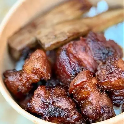 A kraft bowl of caramelised lechon belly over rice