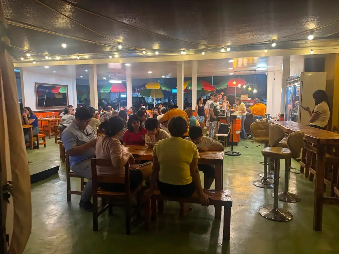 The dining area busy in the evening, string lights across the ceiling